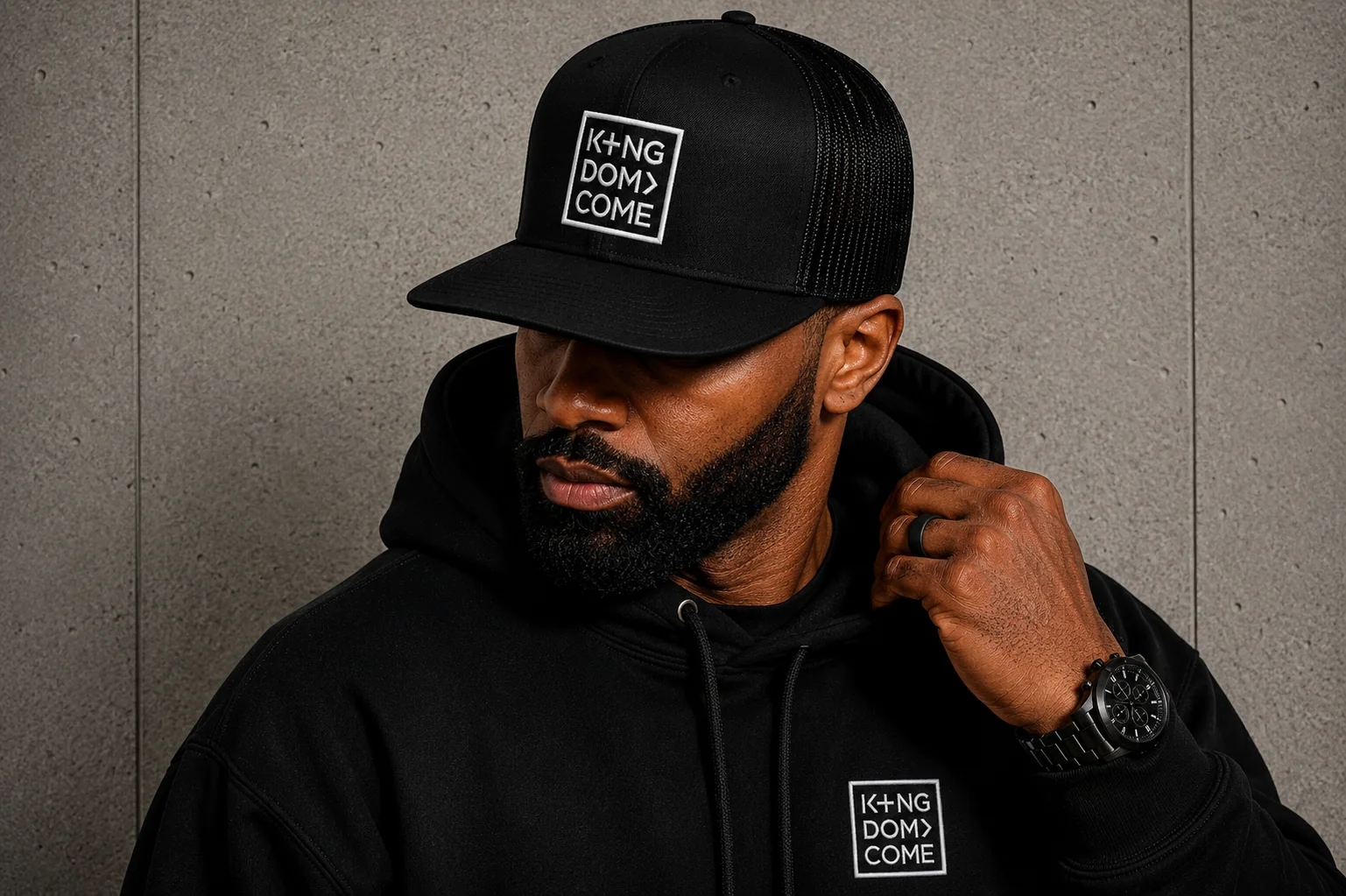 Man wearing the black Kingdom Come trucker cap and hoodie