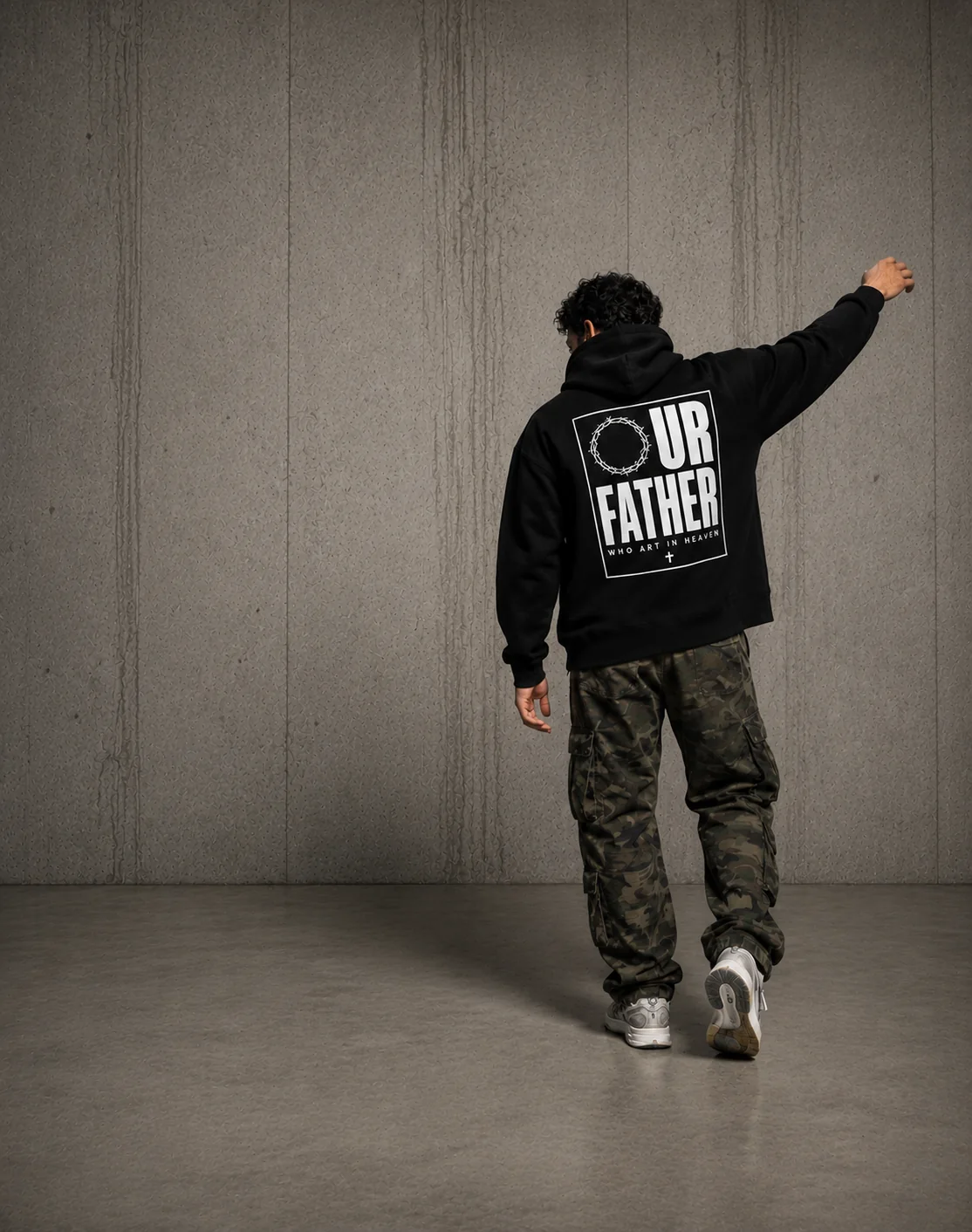 Man walking away wearing the Our Father hoodie with the back print showing